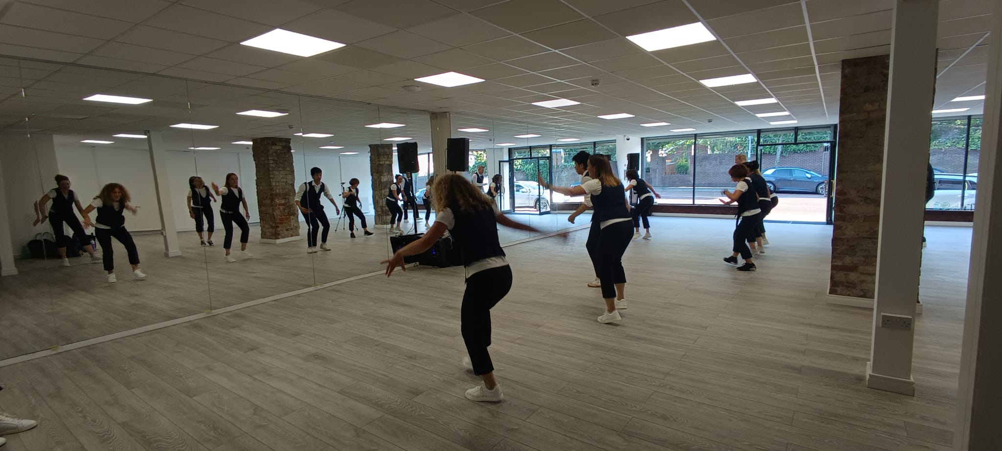 A line of dancers working solo across the Peters Hill floor, arms out, doubled in the full-height mirrors along the wall.