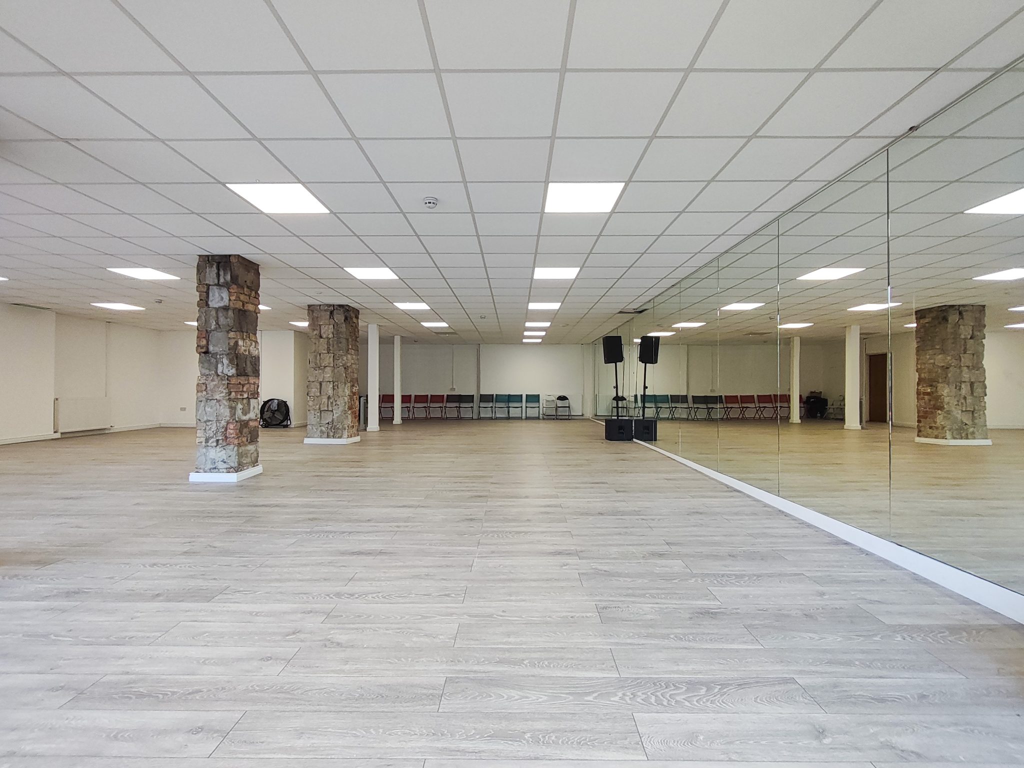 The finished Peters Hill hall: full mirrored wall down one side, new pale wood floor and stone columns.